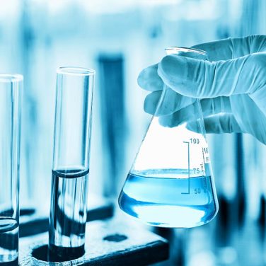 hand of scientist holding flask with lab glassware in chemical laboratory background, science laboratory research and development concept